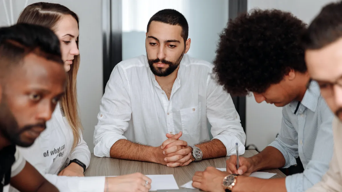 A Middle Eastern man in his 30s is deep in thought in his meeting