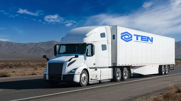 A white tractor with a trailer branded with Trailer Equipment Network's logo with blue sky and wispy clouds in the background.
