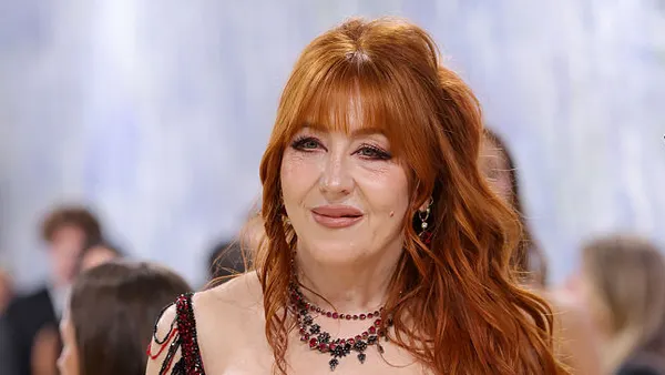 A person with long red hair wears a necklace.
