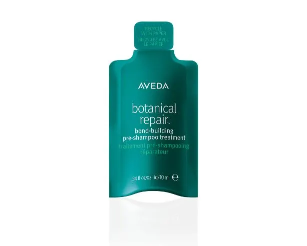 A green, paper-based hair care product sample with Aveda branding and marketing information on the label.