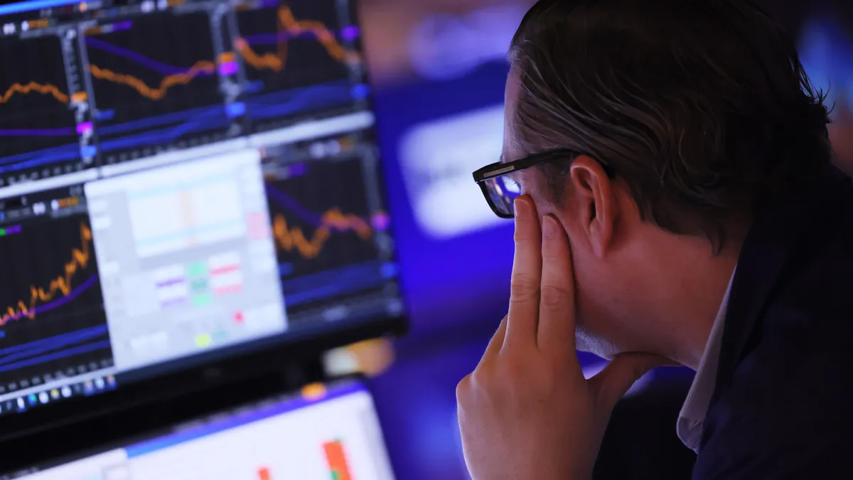 A person looks at stock data on a screen.