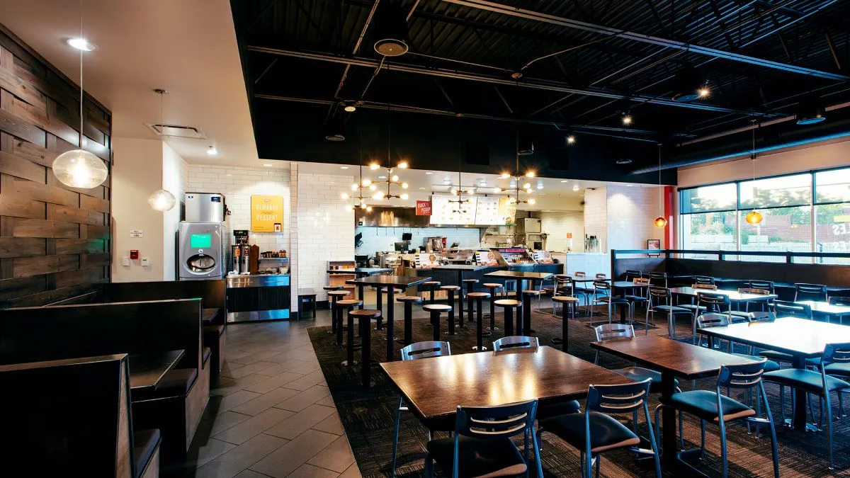 The inside of a Noodles & Company restaurant with views of tables, chairs, booths and the front counter