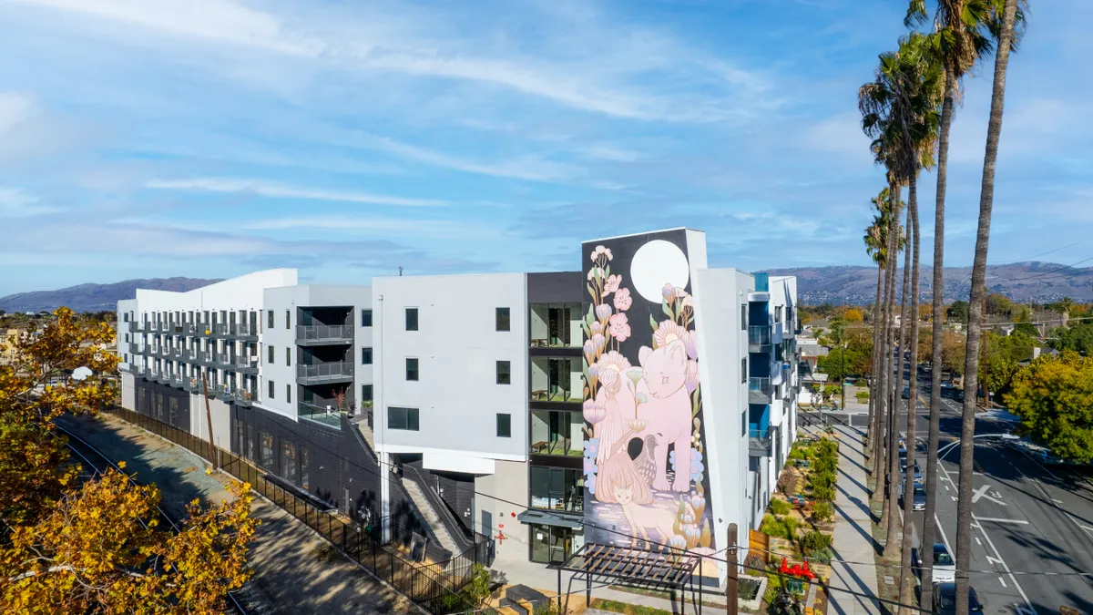 An apartment building with a large mural of a cat on the side.