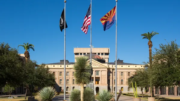 The outside of a building is seen and there are flags on poles in front of the building.
