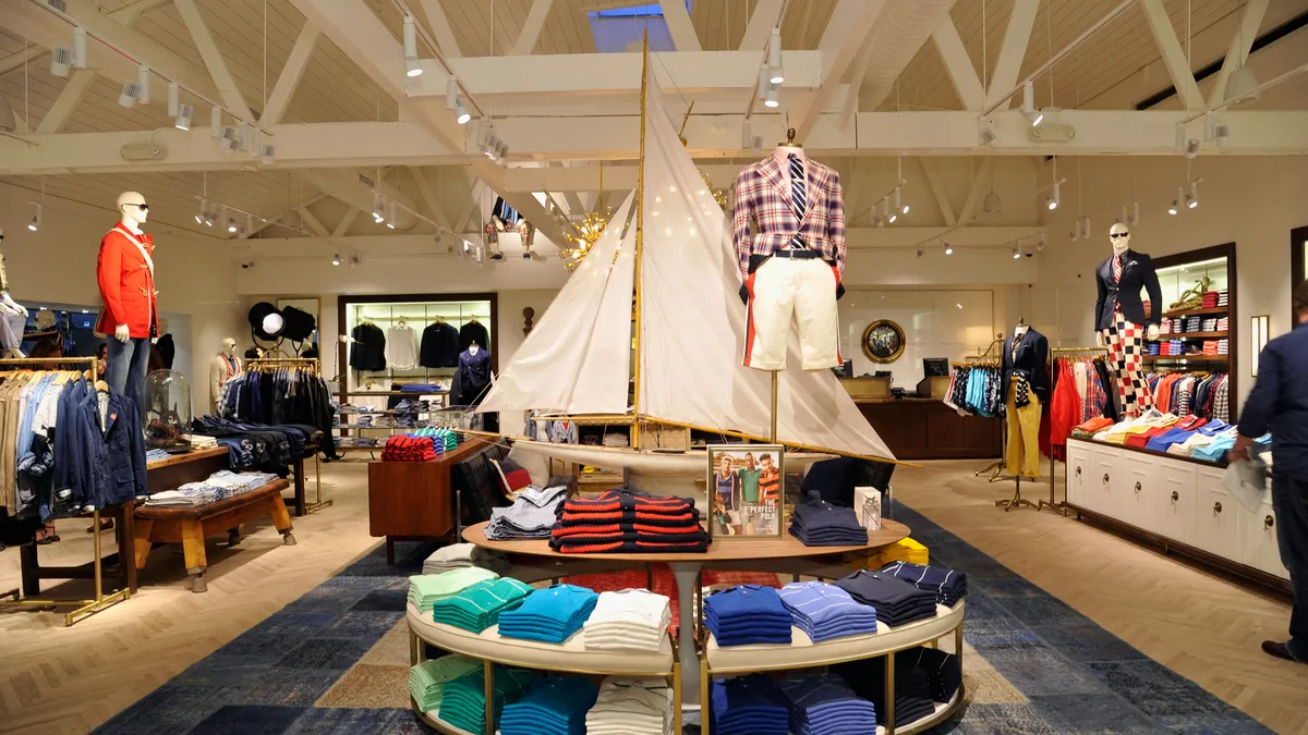 The interior of a Tommy Hilfiger store includes shelves of shirts and mannequins in suit pieces.