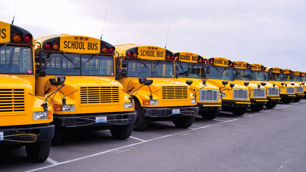 A row of yellow school buses lined up on a parking lot.