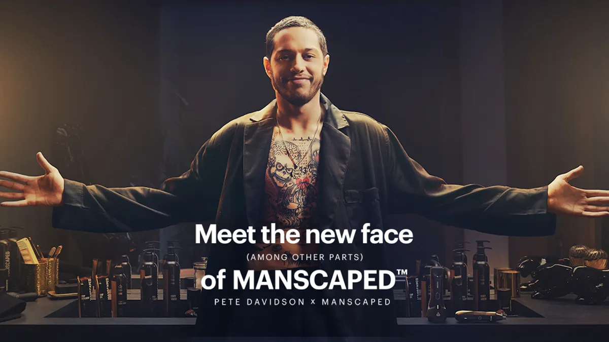 Pete Davidson confidently spreads his arms above a message that announces the comedian's partnership with male grooming brand Manscaped.