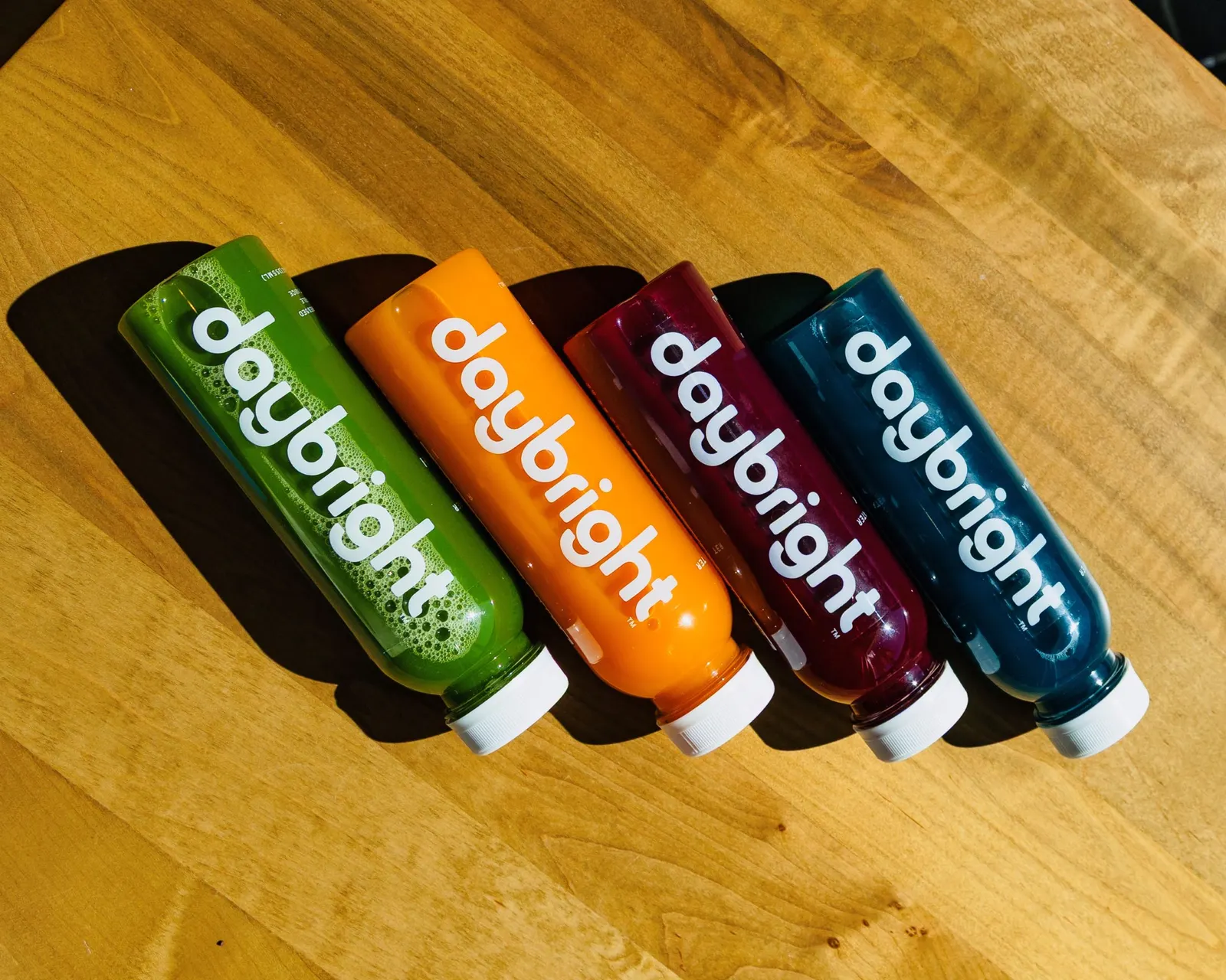 Four different bottles that are green, orange, purple and blue with daybright on the side.