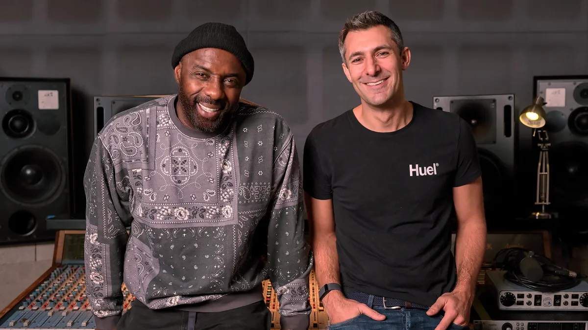 Idris Elba sits next to Huel CEO James McMaster in a recording studio.