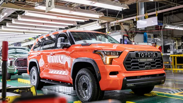 A reddish-orange SUV on a production line in a factory.