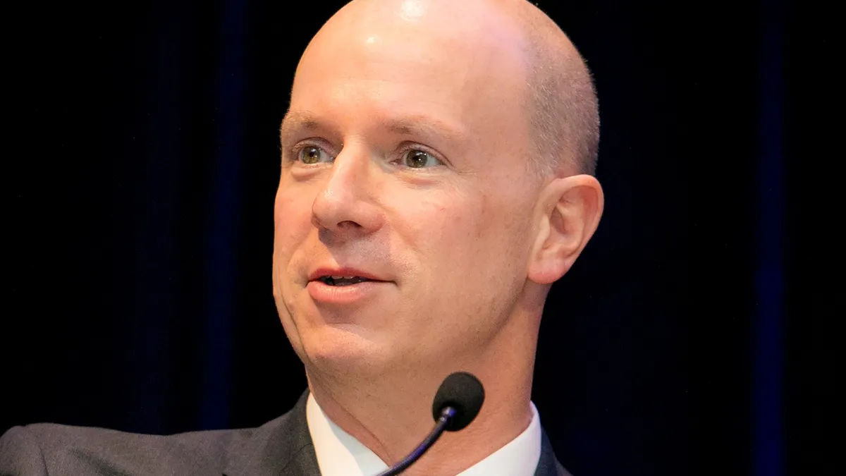 A man in a suit speaks at a lectern