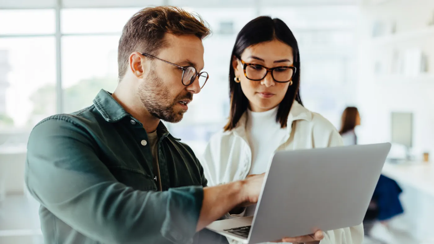 Professionals using a laptop together in an office