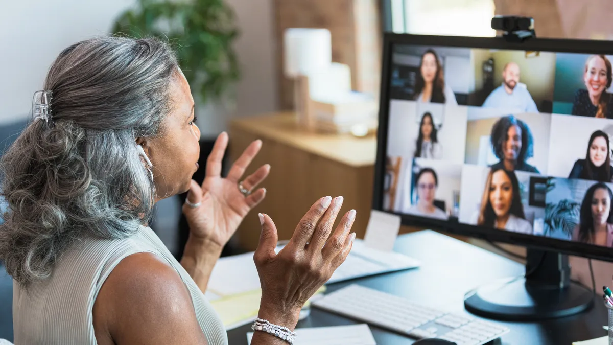 A woman speaks to colleagues on a video connection.