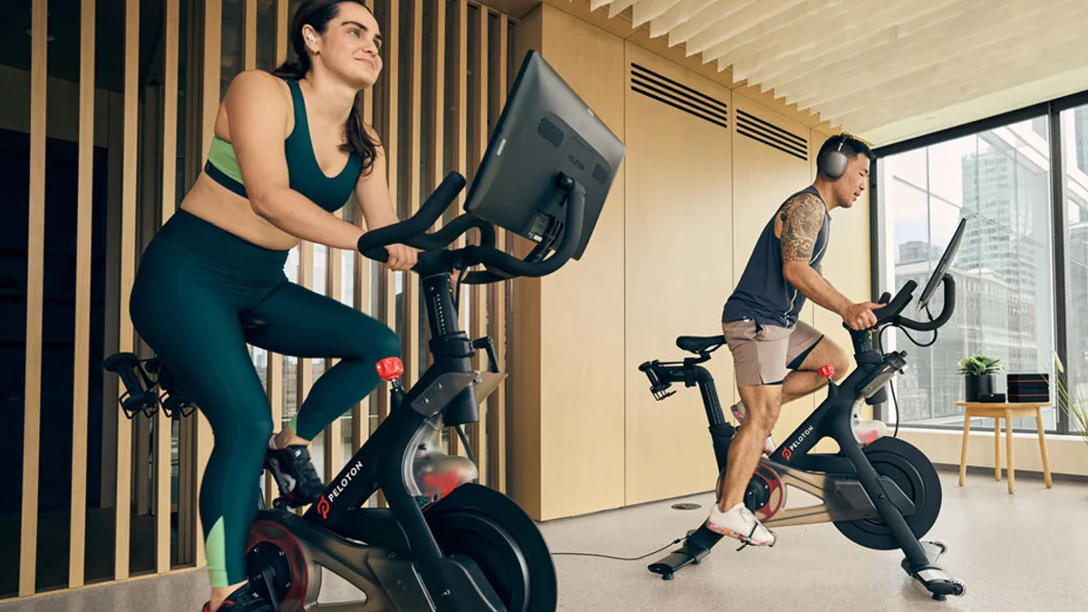 Woman and man cycling on Peloton bikes.