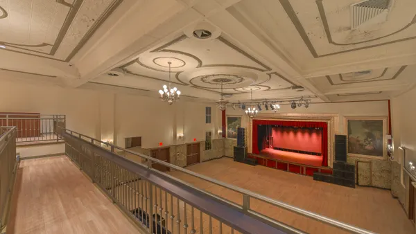 An empty theater is shown in the photo with a stage in the background.