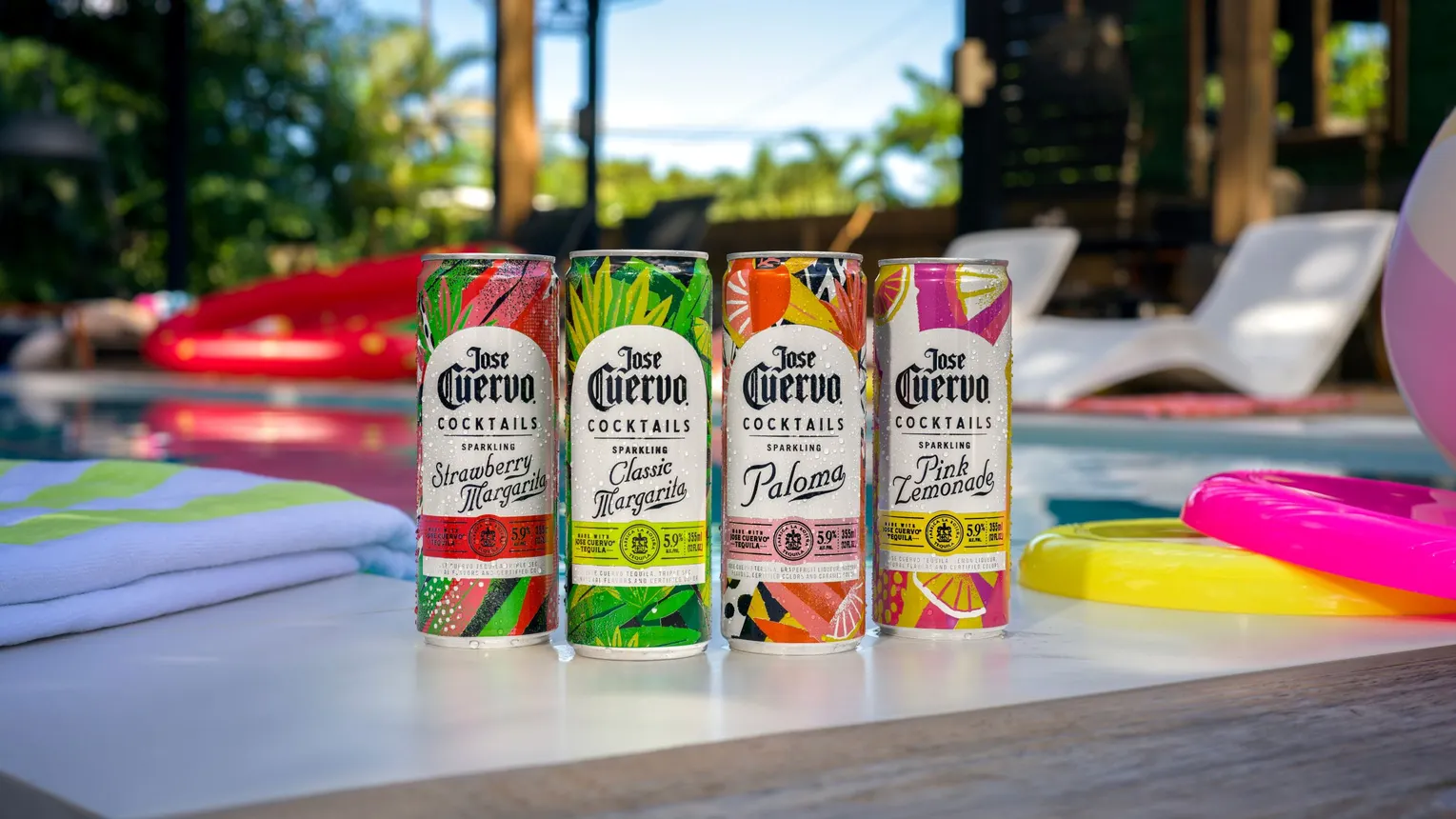Four cans of Jose Cuervo Tequila's canned cocktails sit by a pool.