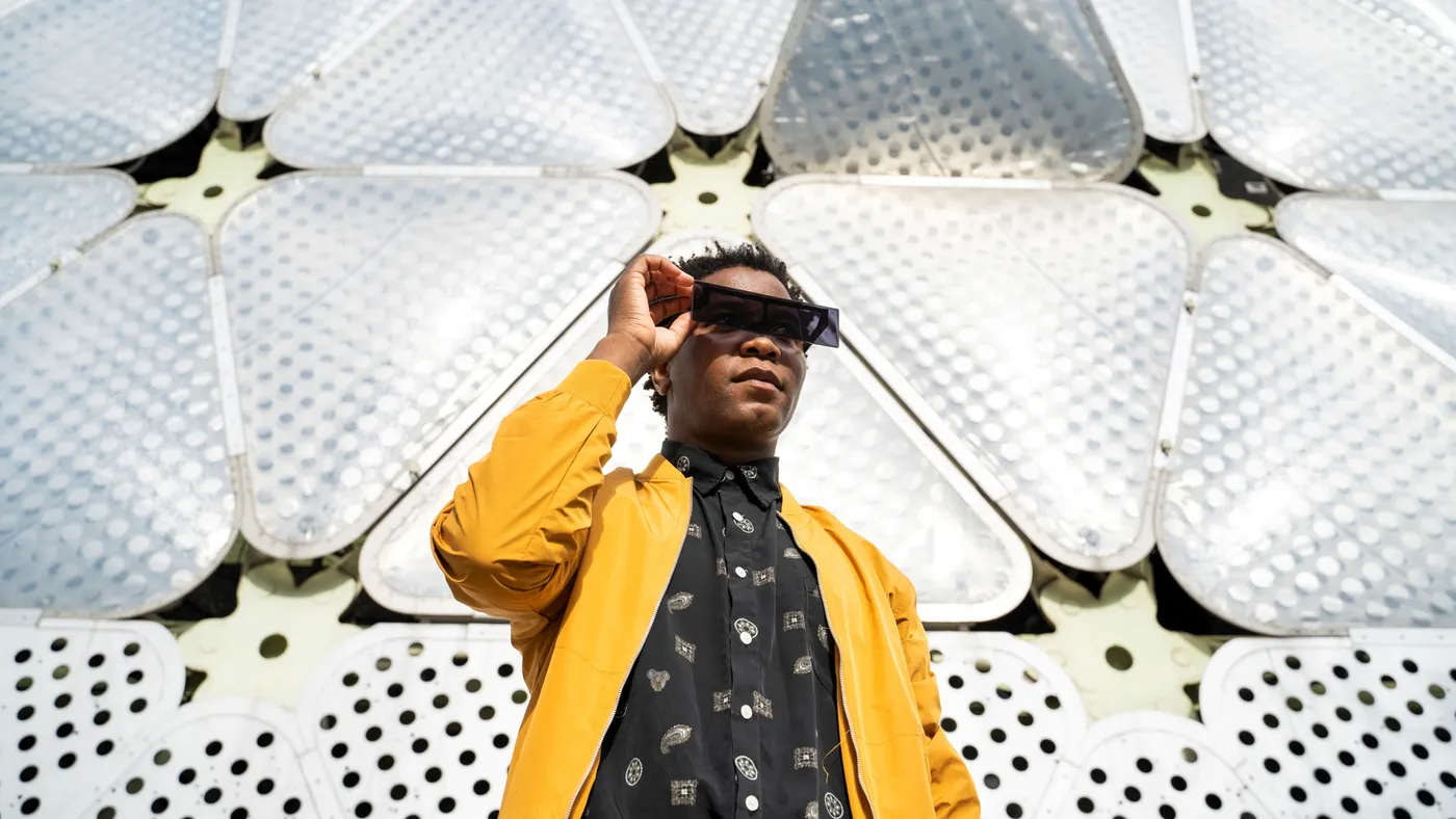 Person with sunglasses standing in front of designed background.