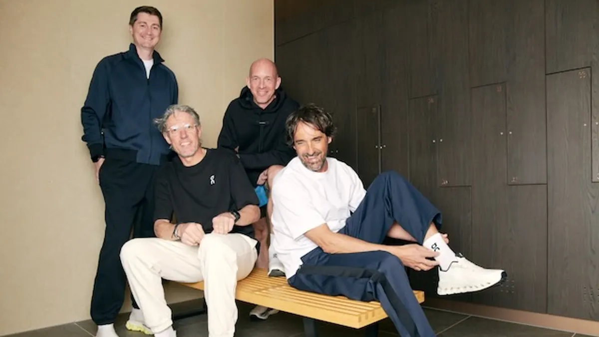 A group of four people in casual clothing, sitting and standing.