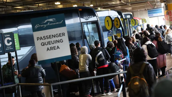 Travelers wait to board Greyhound buses.