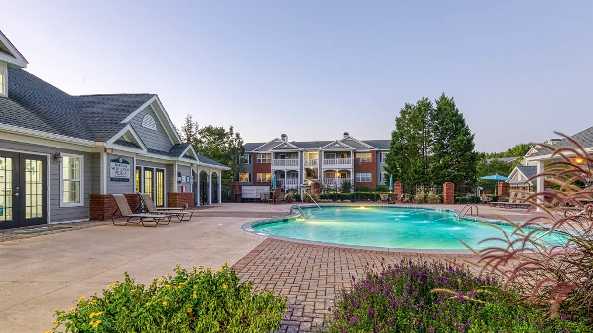 Grey apartment community clubhouse next to a pool.