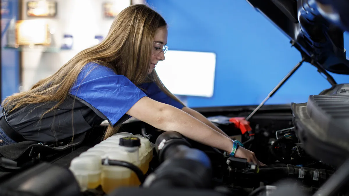 An automotive technician performs work in the engine bay of a vehicle.