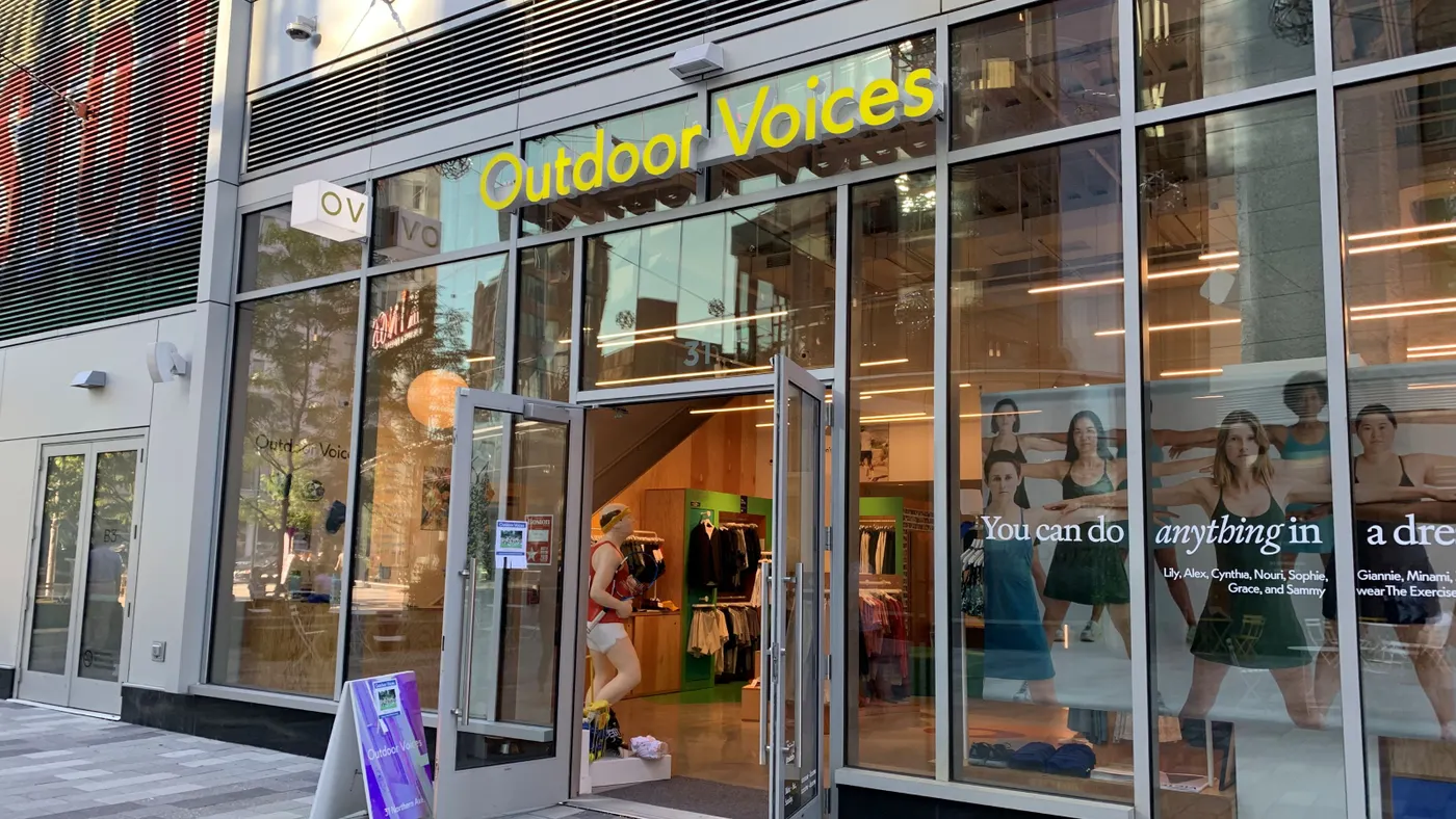 A storefront with main door open, a purple sign in front.