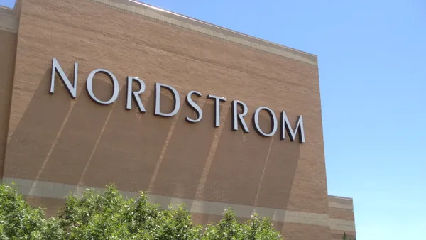 The letters spelling out "Nordstrom" in capital letters create shadows on the brick facade of a store.