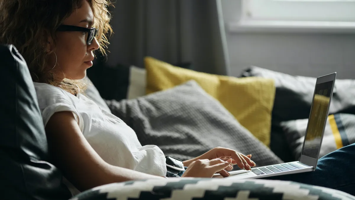 woman uses a computer while sitting on a couch