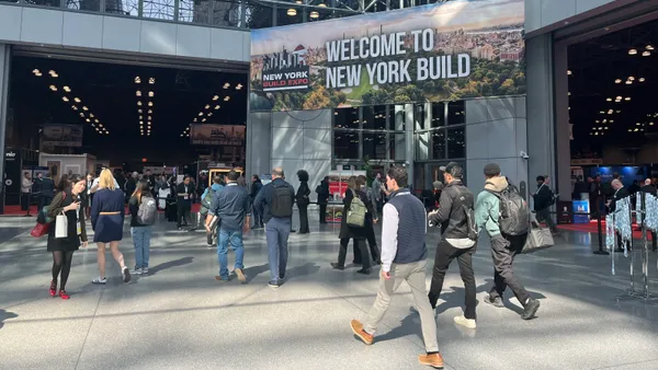 A crowd walks in front of New York Build sign