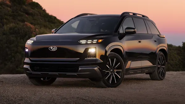 A black 2027 Subaru Getaway electric SUV parked outdoors with an orange sky in the background.