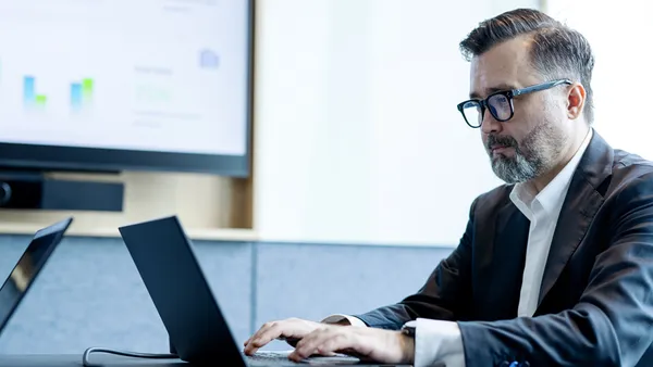 A business professional on their laptop in a work meeting