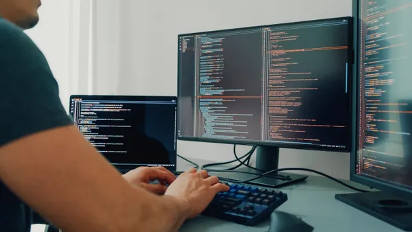 Closeup young man software developers using computer to write code application program for AI technology development at desk with multiple screens work at home office.