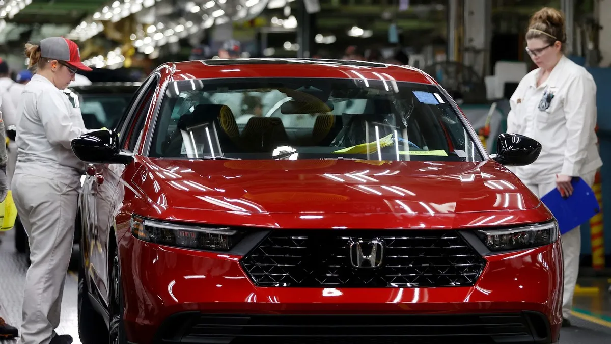 Two workers inspect a 2023 red Honda Accord at the automaker's Marysville Auto Plant in Ohio.