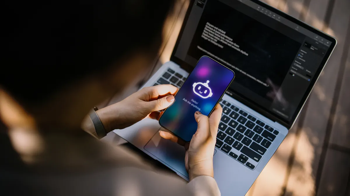 Businesswoman using Chatting AI chatbot virtual assistance app on smartphone to assist her while working on laptop in office park. Using AI technology at work. Online robot system. Concept of VR and AR technologies. People, AI, innovation and technology