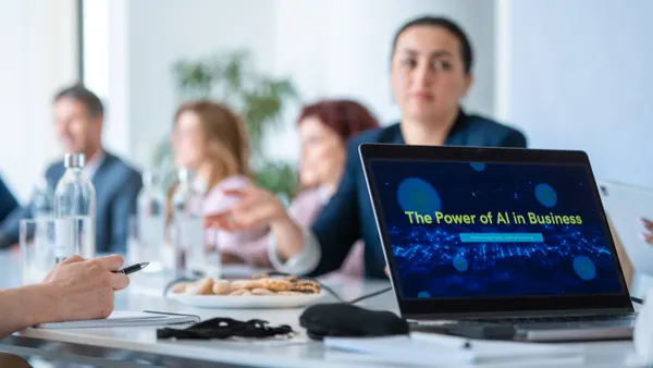Business professionals seated in a modern boardroom interact during a laptop-based AI presentation.