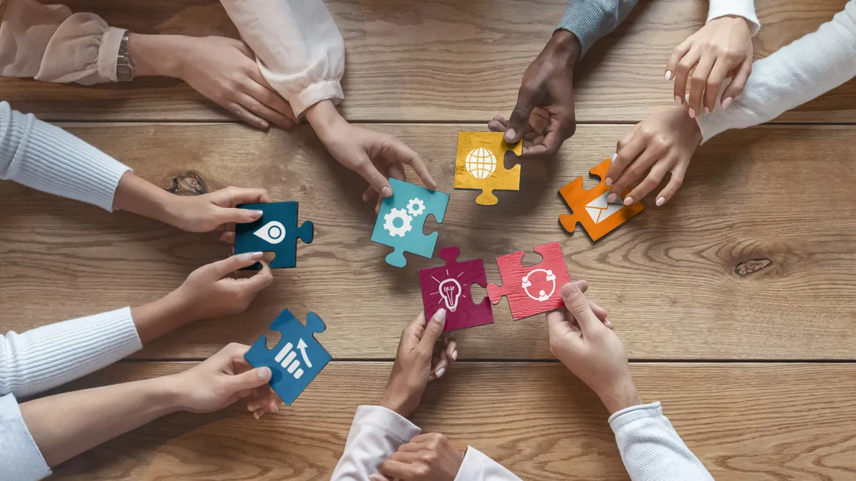 High angle shot of people reaching to connect puzzle pieces together