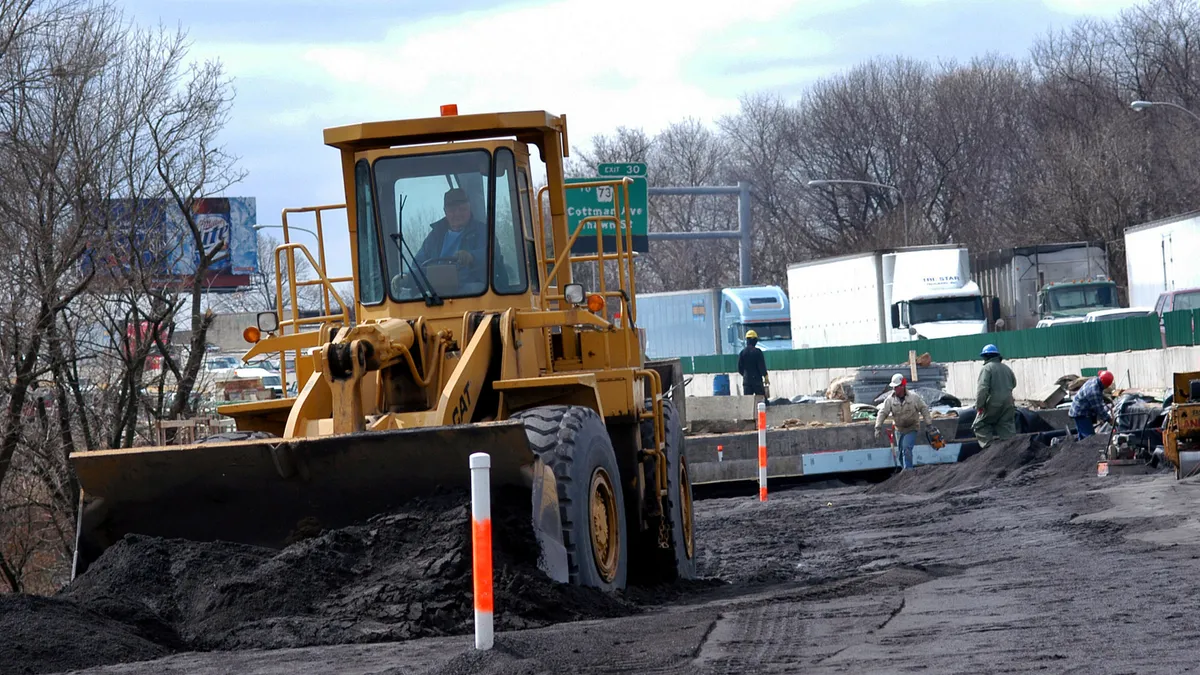 A construction worker operates a bulldozer while moving pebbles as part of a construction project on Interstate-95.