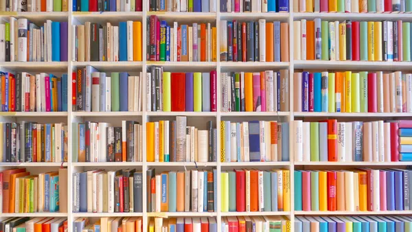 A packed bookshelf with very colorful book spines.