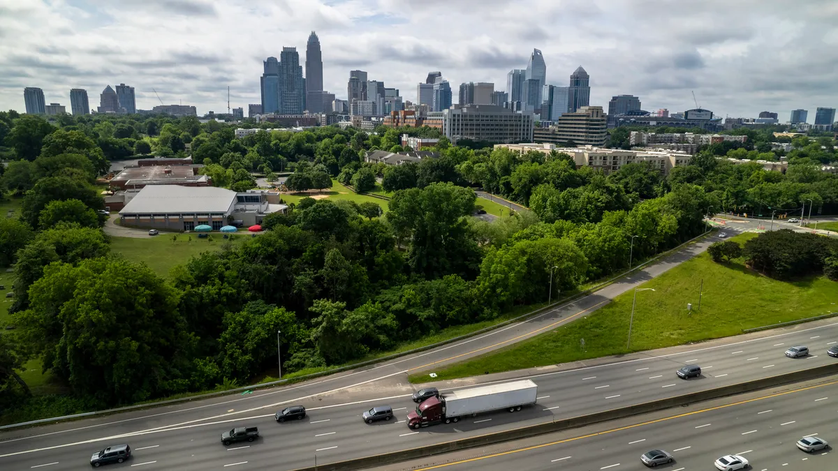 A truck and other vehicles drive on a highway with the Charlotte, North Carolina, skyline in the background in an aerial photo.