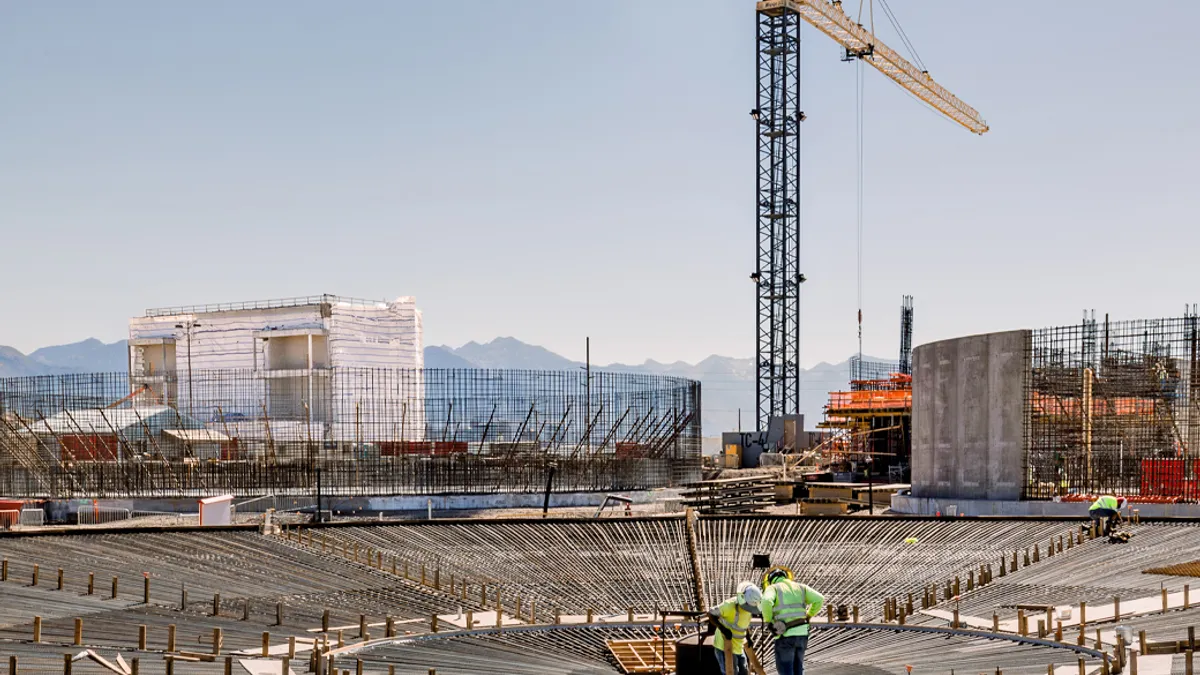 Construction workers wearing hard hats and reflective vests working at a busy construction site.