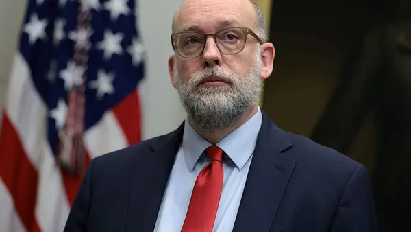 Russ Vought, Trump administration official, stands in front of an American flag.