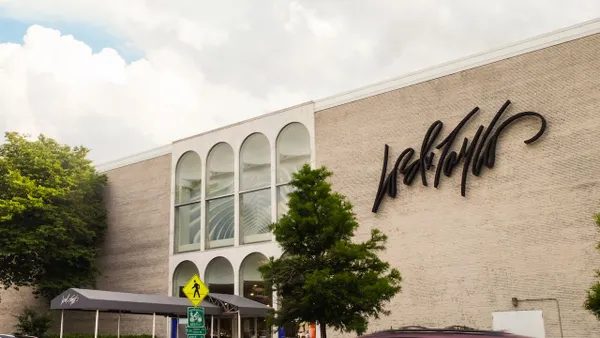 Puffy clouds and green trees frame a suburban department store building.