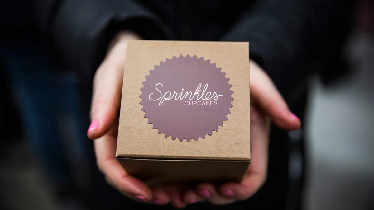A person holds up a box that say Sprinkles