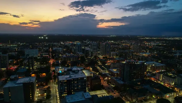 High angle view of illuminated city against sky at sunset.