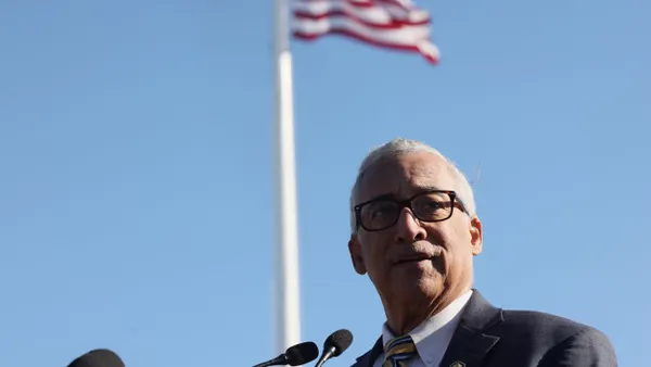 Bobby Scott speaks into a microphone while the American flag flies in the background.