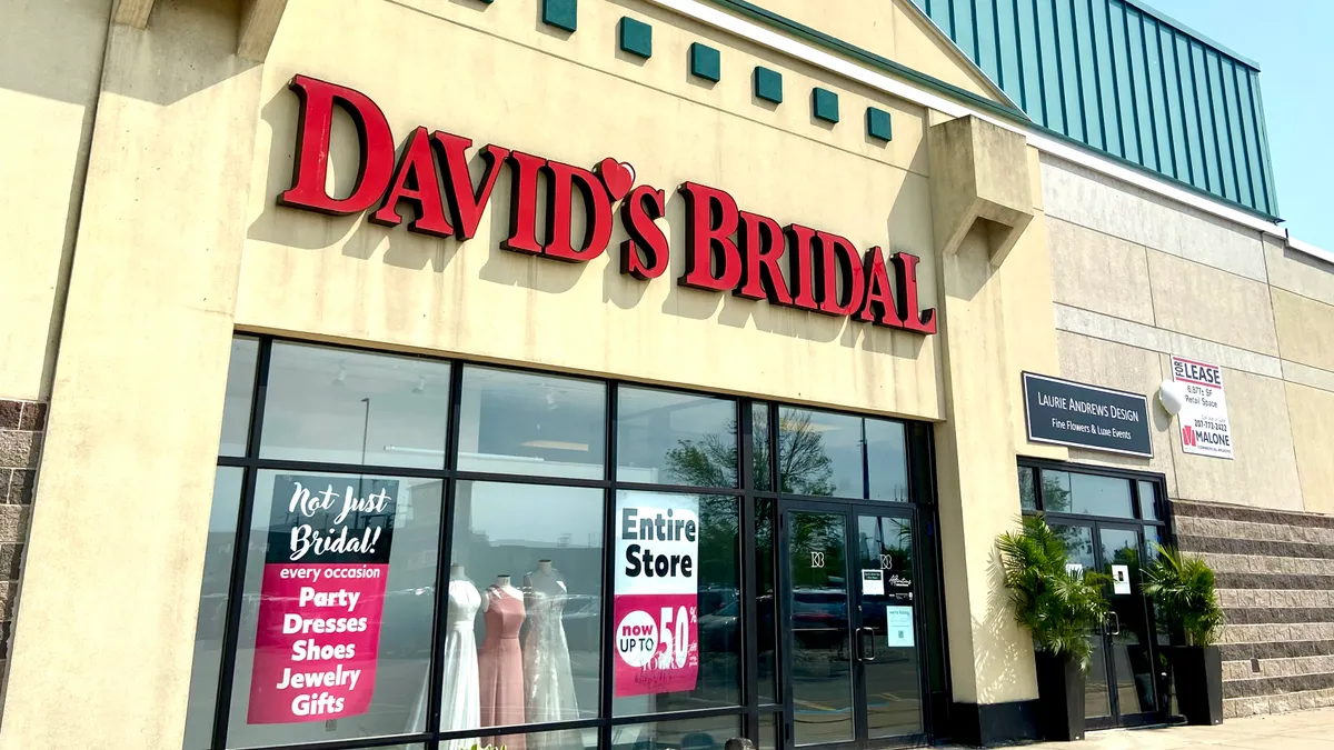 A storefront of a David's Bridal retail store with sale signs.