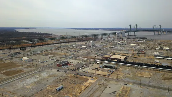 An overhead view of chemical manufacturing site next to a brige and a body of water.