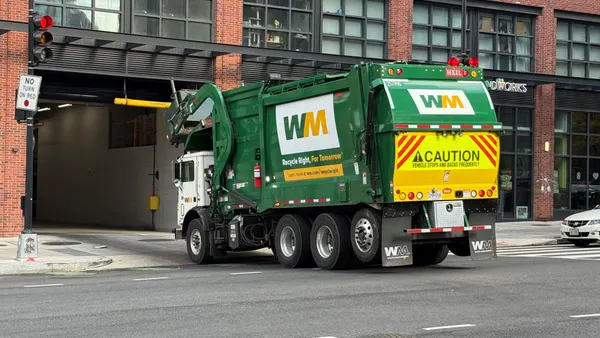A trash truck enters a loading dock of a building in a city