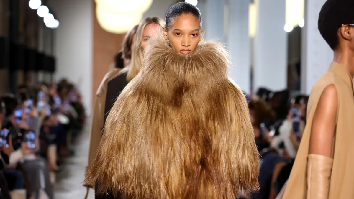 A model is a voluminous fur coat walks down a runway.
