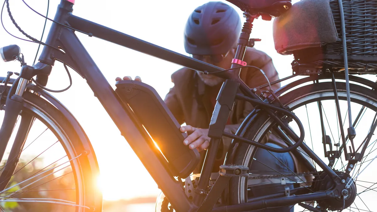 A photo of a man changing an electric bicycle battery.